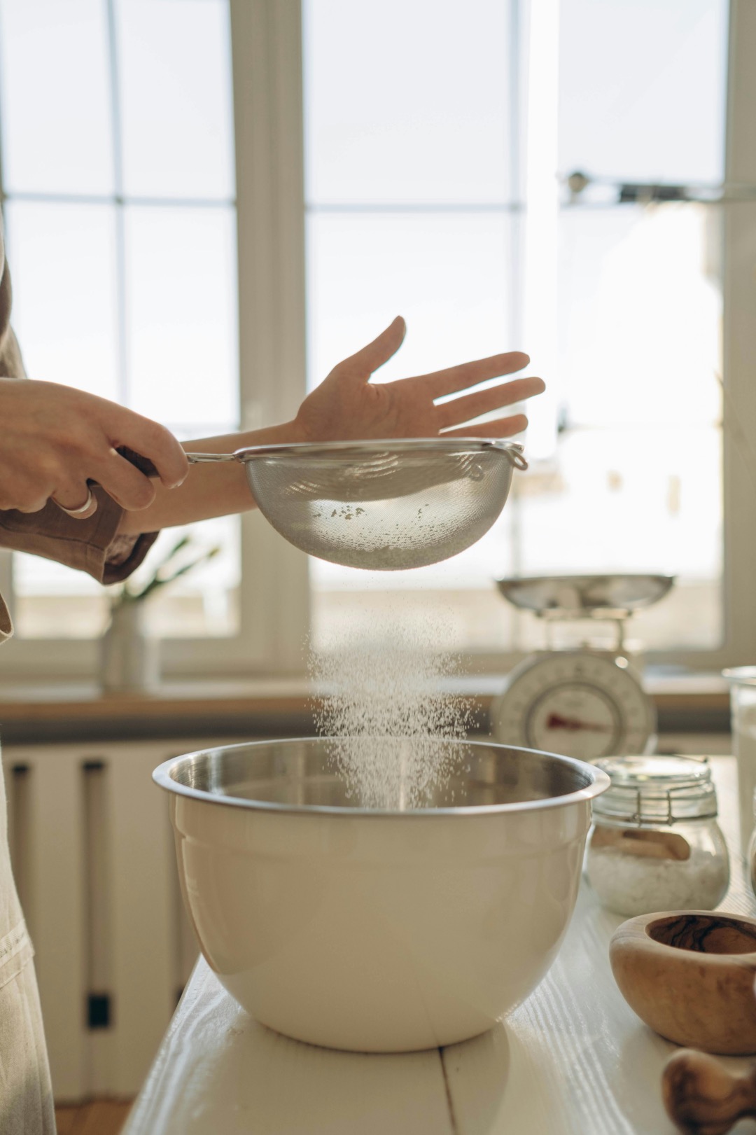 Sifting flour into a bowl to make louise cake slice