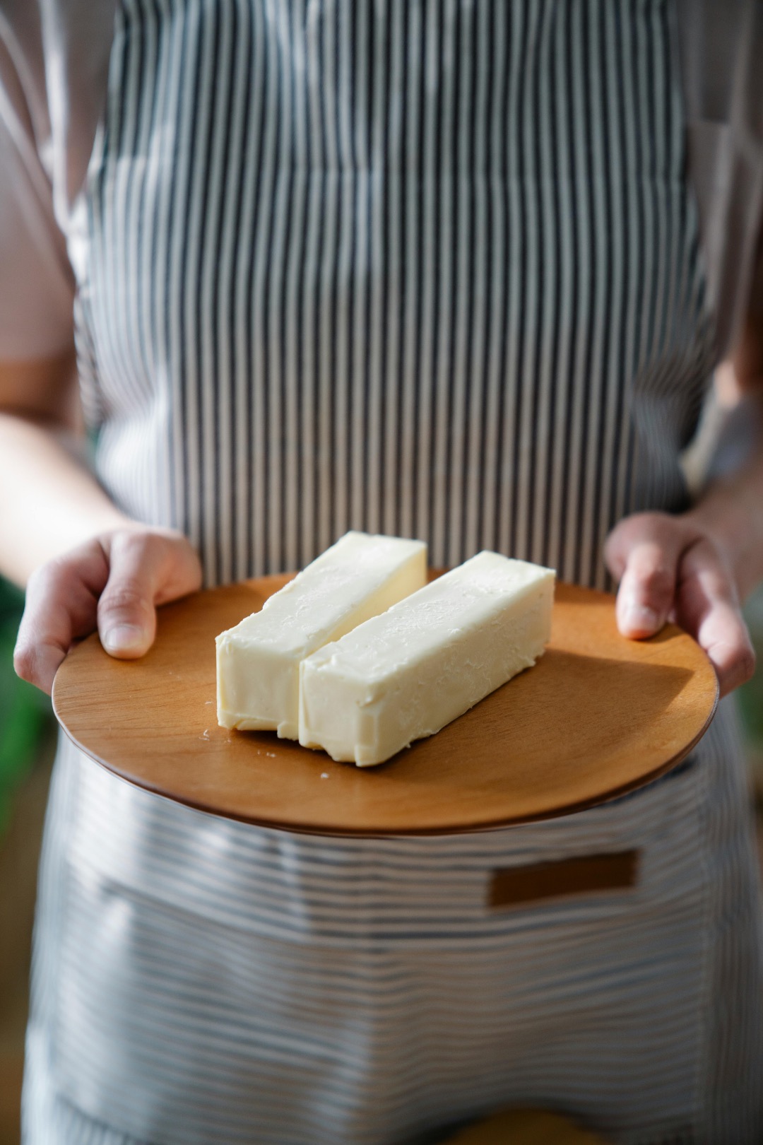 Person holding a plate with room temperature butter on it