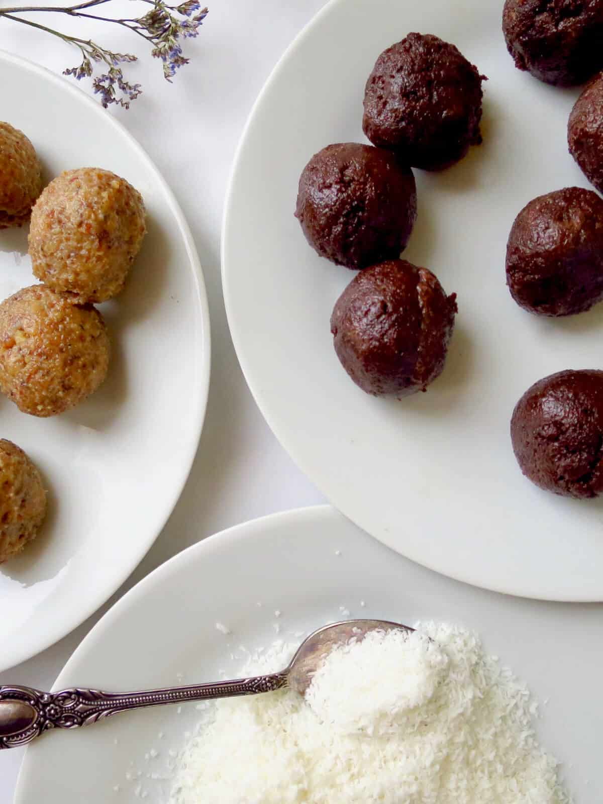 Uncoated carrot and chocolate cake balls on a plate with a bowl of coconut ready to coat the cake balls in