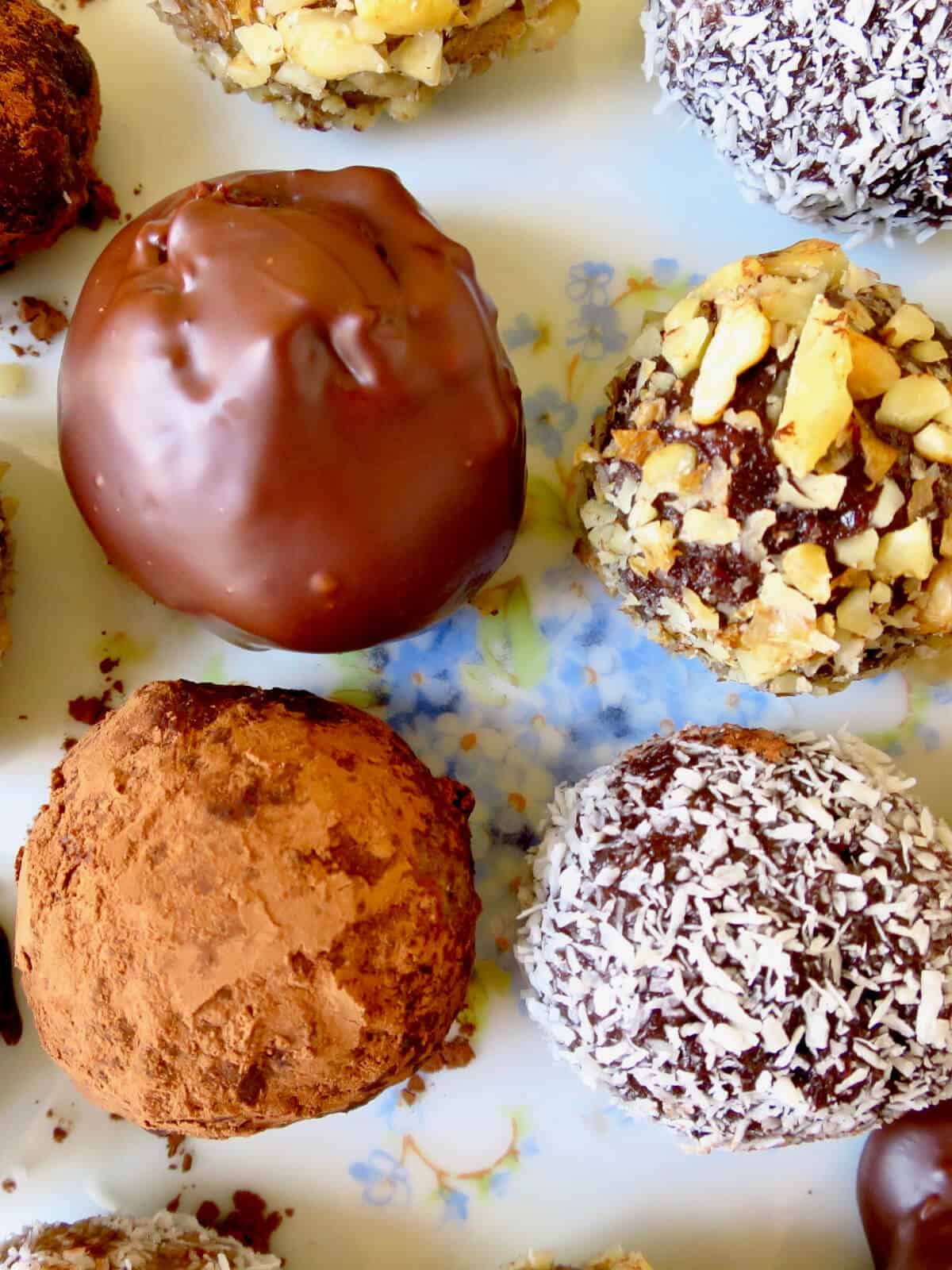 Close up of cake balls in different coatings: chocolate ganache, cocoa power, coconut and chopped nuts.