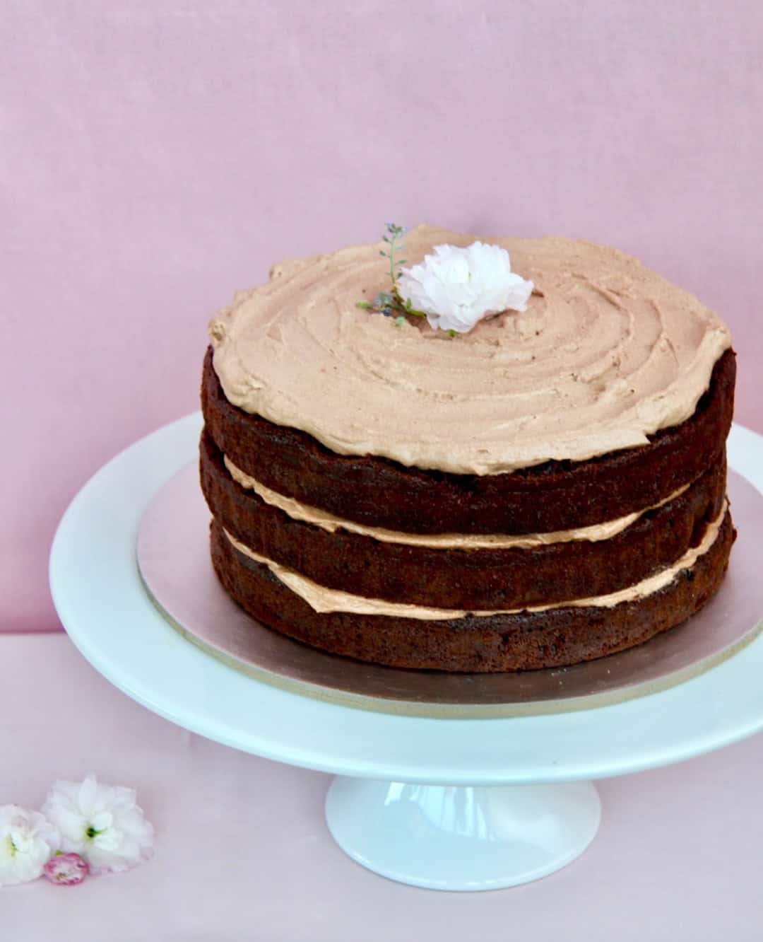 chocolate layer cake on a cake stand disguising the hole