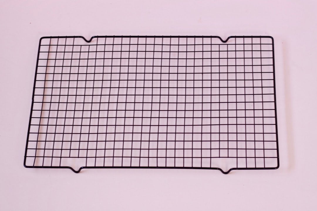 Black cooling rack on a pink board.