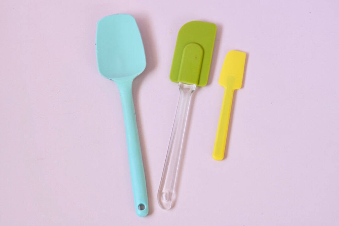 Three spatulas laid out on a pink board