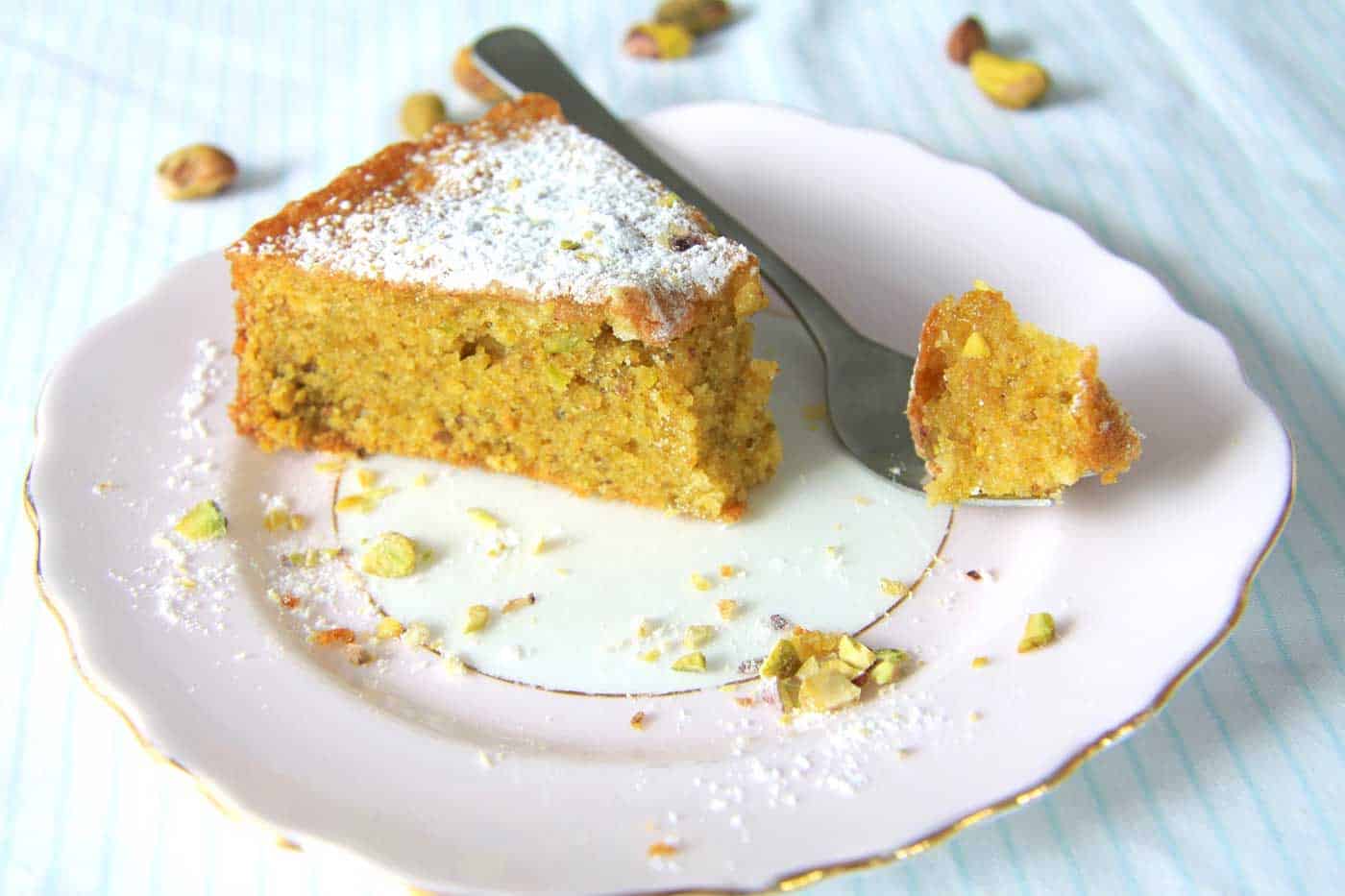 A slice of Pistachio cake with a fork -full of cake ready to eat.