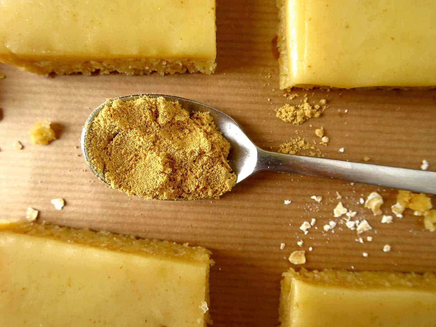 A teaspoon with ground ginger and Ginger Crunch pieces around it