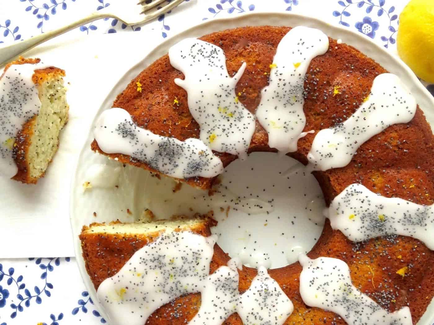 Lemon poppy seed ring cake with icing drizzled on it and a piece of it served.