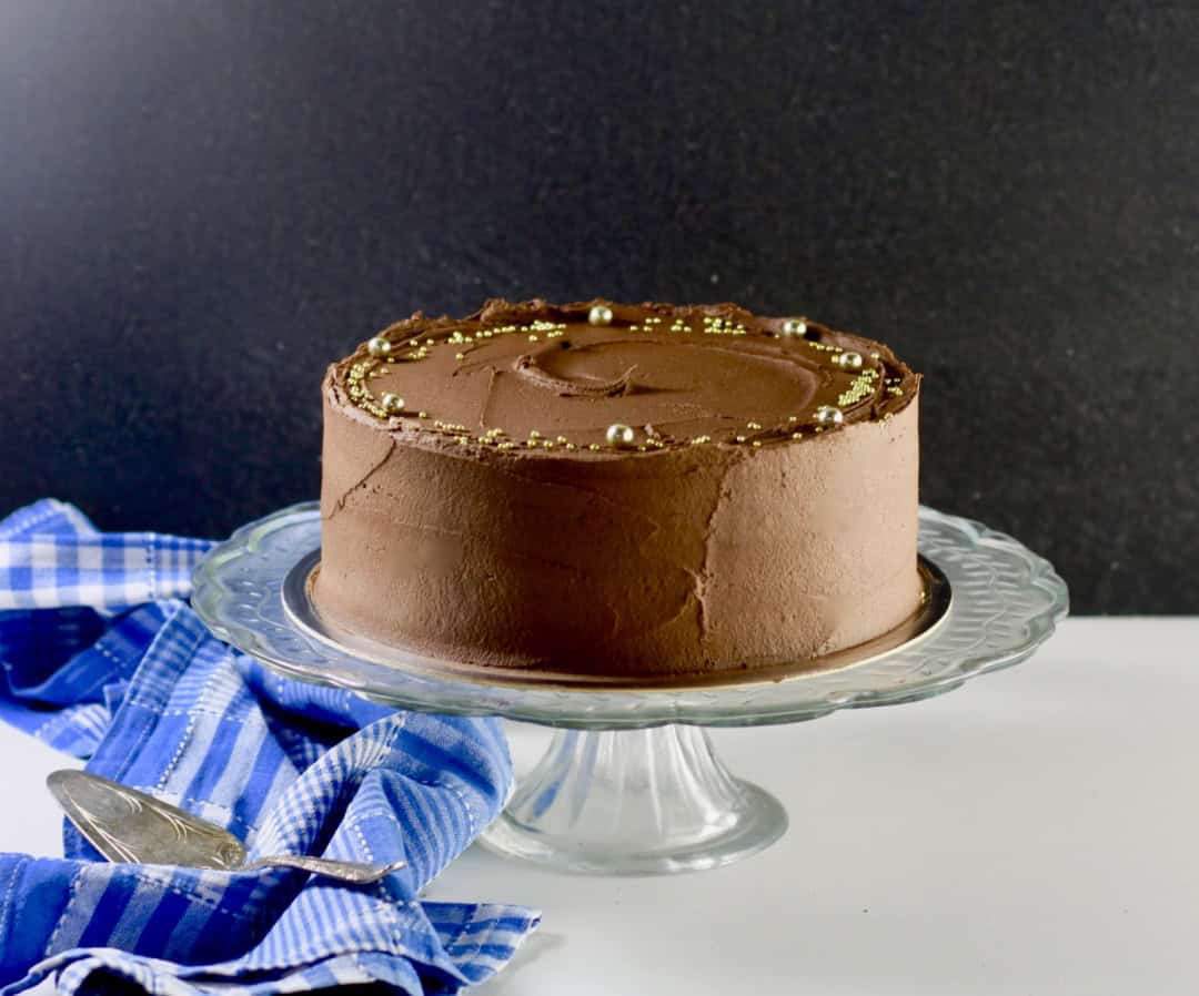 Fully iced chocolate cake on a cake stand.