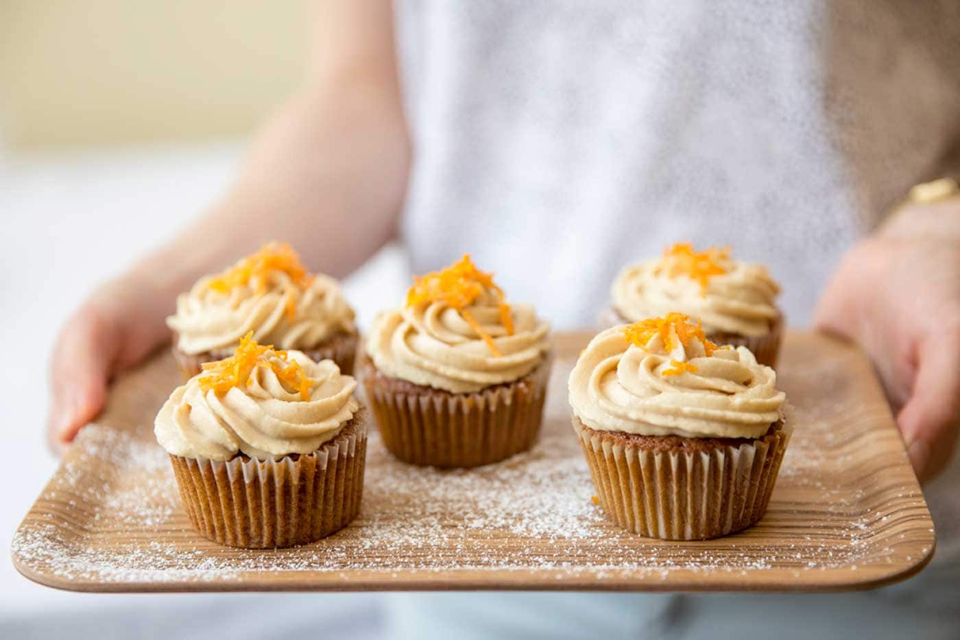 A person holding a tray of cupcakes.