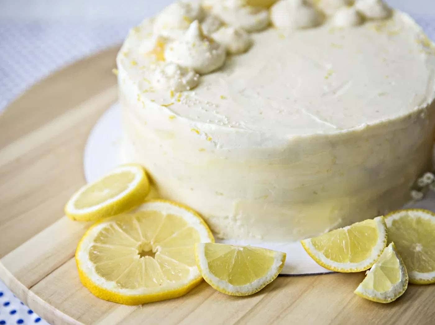 Fully iced lemon layer cake with lemon wedges