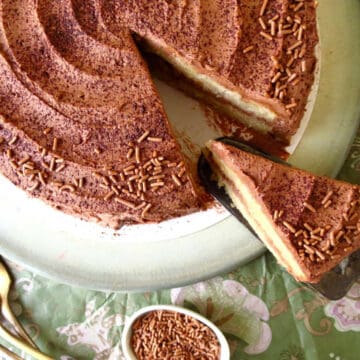 Banana chocolate cake which has been cut and about to be served. a little dish of chocolate hail next to it.