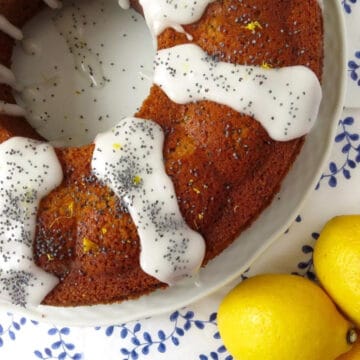 A close up of lemon poppy seed cake with icing drizzled on it poppyseeds sprinkled on top.