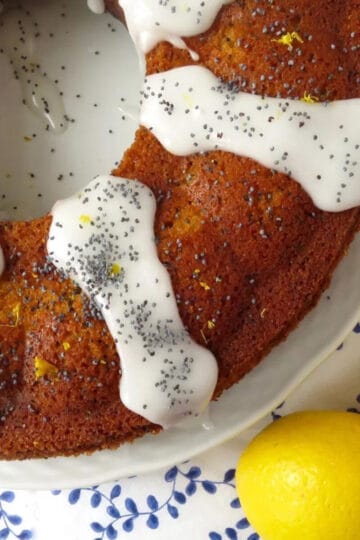 A close up of lemon poppy seed cake with icing drizzled on it poppyseeds sprinkled on top.