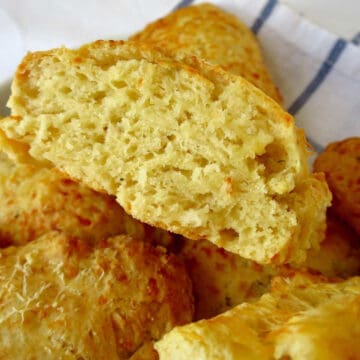 Fluffy cheese scones in a pile. The top one has been cut in half.