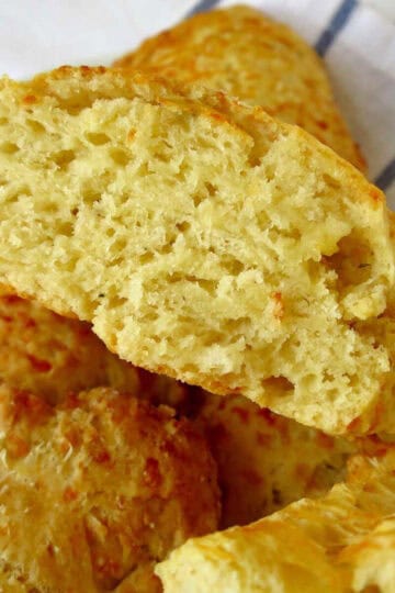 Fluffy cheese scones in a pile. The top one has been cut in half.