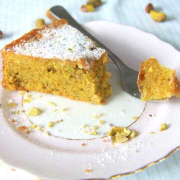Moist as ever Pistachio cake slice on a plate with a fork.