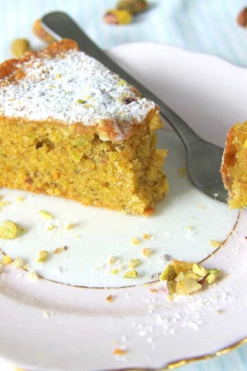Moist as ever Pistachio cake slice on a plate with a fork.