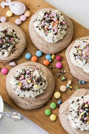 A board of Easter meringue nests fully decorated with whipped cream and sweets.