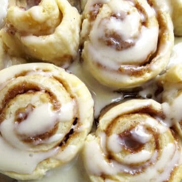 Four yummy cinnamon rolls with a glossy glazer drizzled over them.