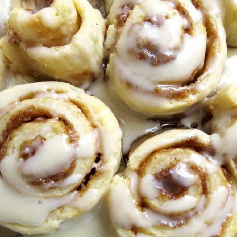 Four yummy cinnamon rolls with a glossy glazer drizzled over them.