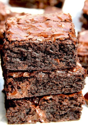 Three pieces of fudgy cocoa brownies stacked on top of eacher. Gooey chocolate oozes out of each piece.