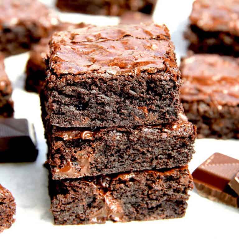 Three pieces of fudgy cocoa brownies stacked on top of eacher. Gooey chocolate oozes out of each piece.