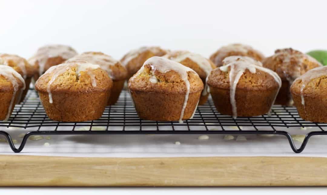 12 glazed feijoa muffins on a cooling rack.