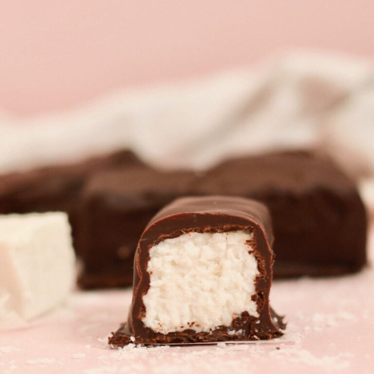 A perfectly formed homemade bounty bar which has been cut in half. It showcases an outer casing of chocolate which is filled with coconut bounty filling.