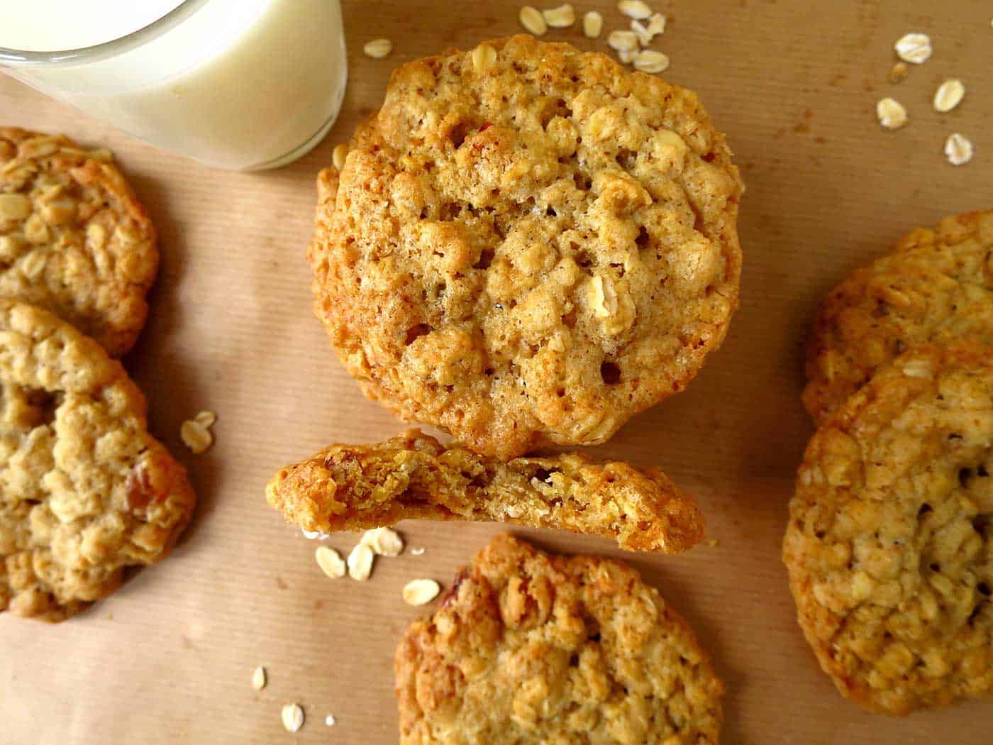 Oatmeal cookies on brown paper with a glass of milk.