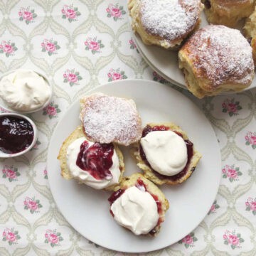 Perfect lemonade scones on a plate. Two have been cut and presented as both Devonshire (jam on top of cream) and Cornish style (cream on top of jam).