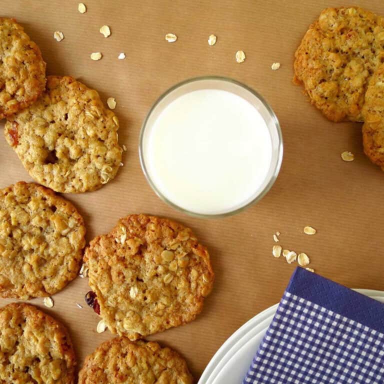 Oatmeal cookies and a glass of fresh milk on brown baking paper.