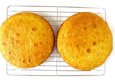 Two fully baked cakes layers on a cooling rack.