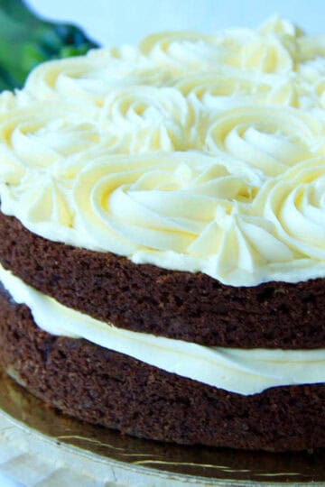 A two layer Zucchini Chocolate Cake decorated with buttercream piped rosettes and filling.
