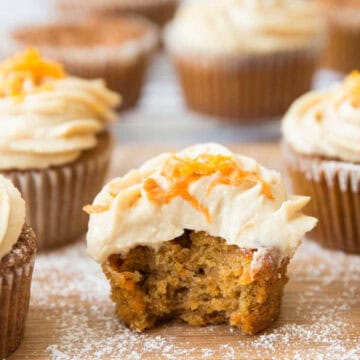 A carrot cupcake frosted with cream cheese cut in half.