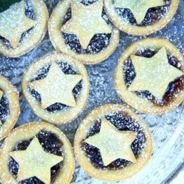 Christmas Mince Pies sprinkled with icing sugar on a glass plate.