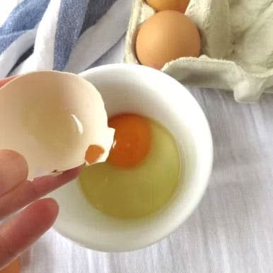 Removing a piece of egg shell from a cracked egg with a larger piece of egg shell