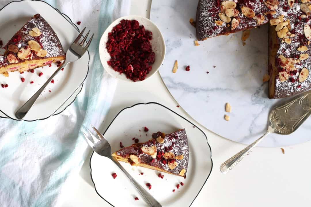 Gluten dairy free almond raspberry cake served on plates. Toasted almonds and berry powder are sprinkled on top.