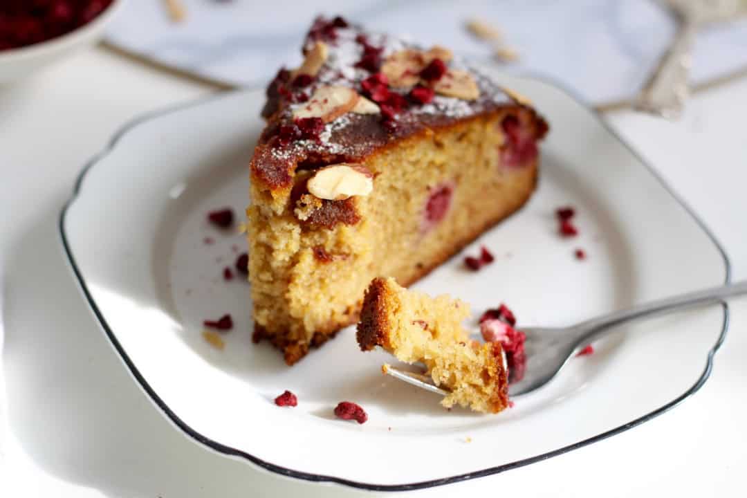 A piece of delectable gluten dairy free almond raspberry cake up close. It has a super moist texture.