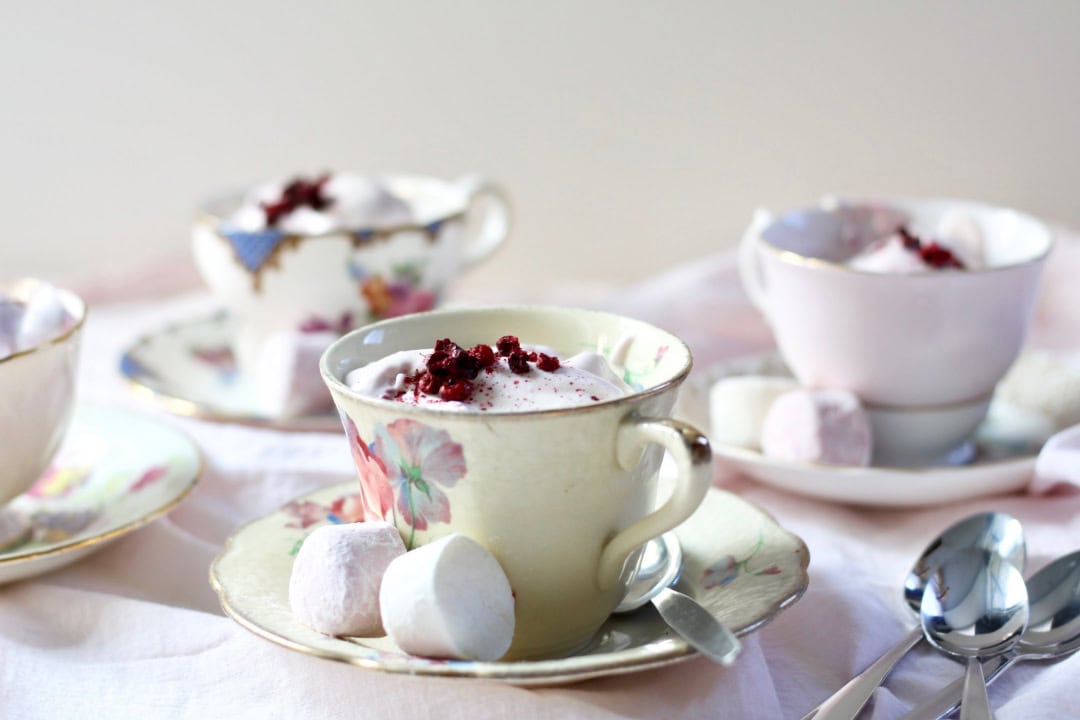 Four teacups and saucers filled with berry ambrosia dessert.