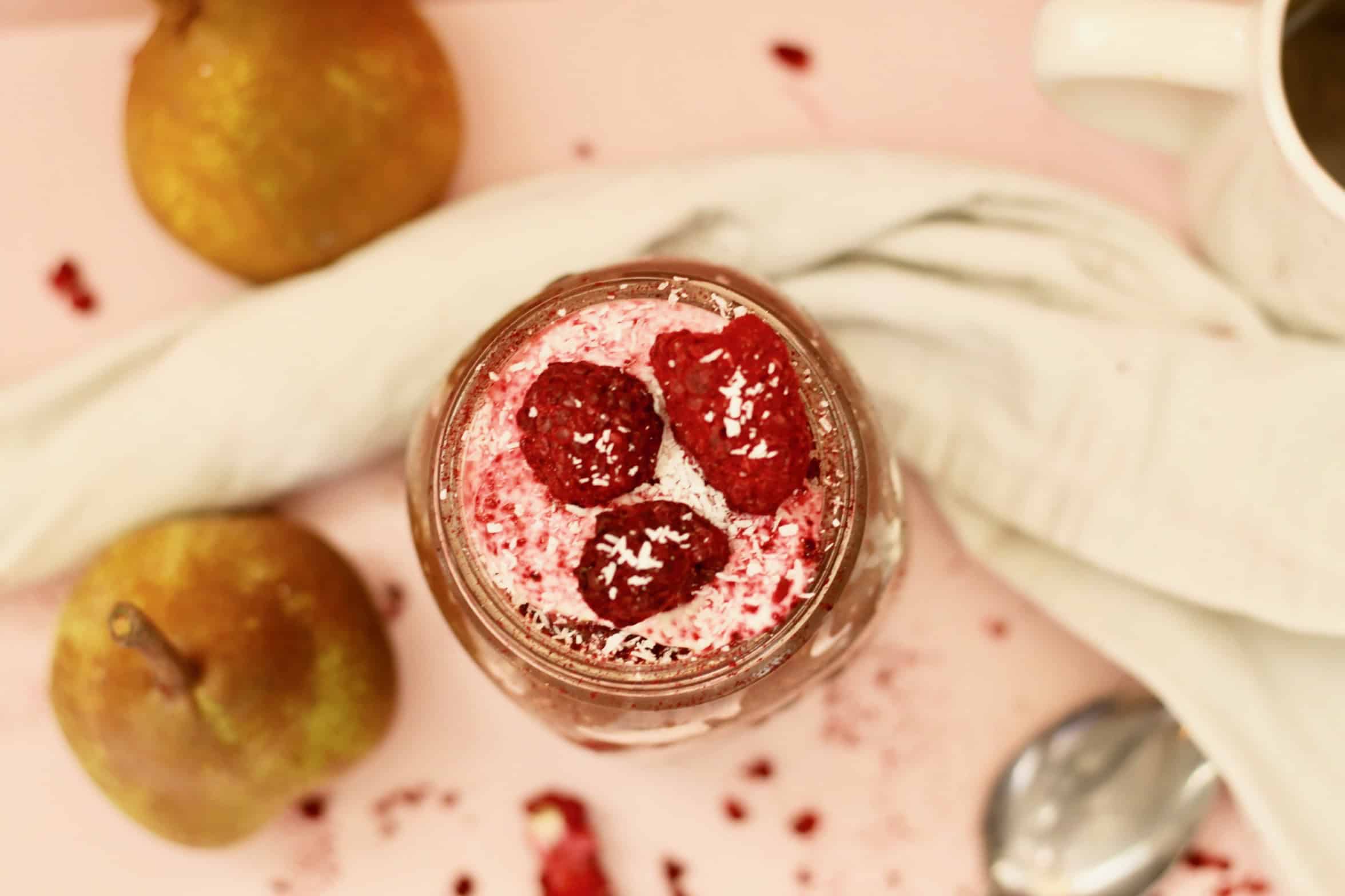 Birds eye view of chocolate coconut bircher muesli. Berries and coconut scatter around.