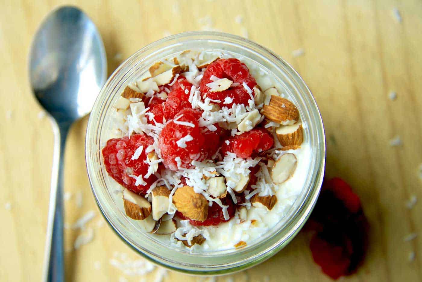 Top view of raspberry slice overnight oats. Raspberries, coconut and chopped almonds are generously sprinkled on top.