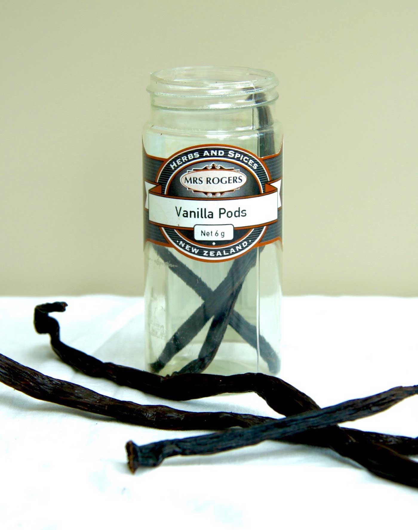 Mrs Rogers vanilla pods in a container with some pods out of the container to show what they look like.