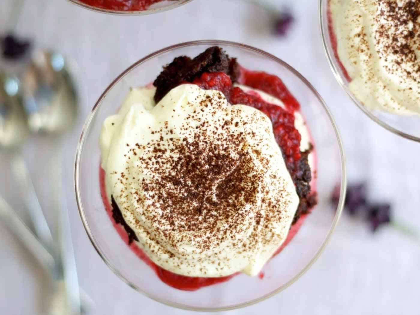 Top view of berry trifle with fresh whipped cream on top sprinkled with cocoa powder.