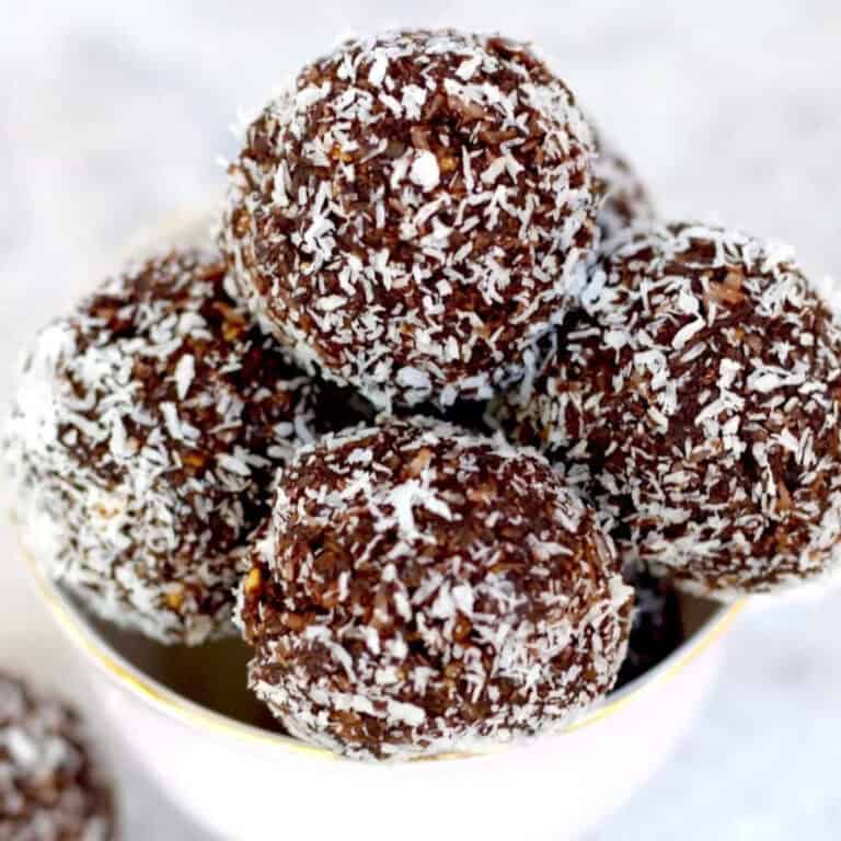 Chocolate vegan bliss balls in a pink tea cup which have been rolled in coconut.