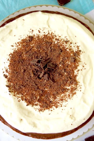 A top view of the velvet chocolate cheesecake. It has a creamy sour cream topping which is decorated with chocolate shards.