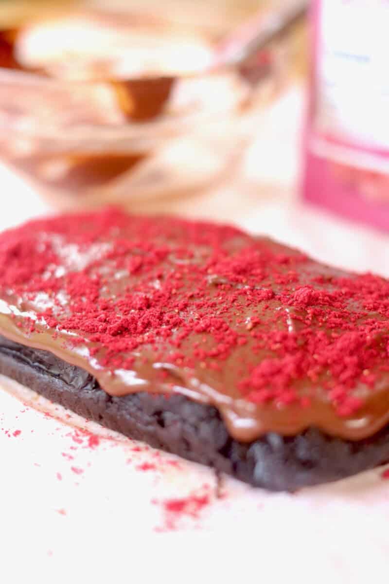 A side view shot of the vegan chocolate brownie all frosted and dusted with fresh freeze dried berry powder.