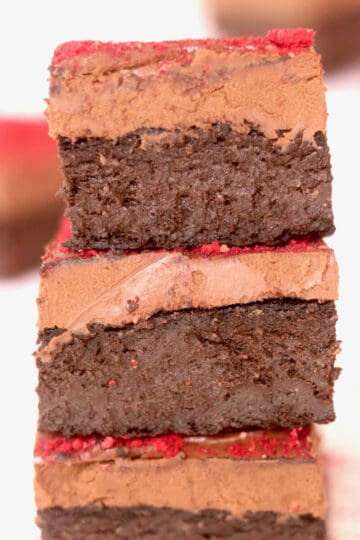 Three pieces of decadent chocolate vegan brownies. A thick layer of vegan chocolate ganache is layered on each piece.