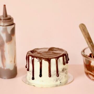 A cake topped with a delicious chocolate drizzle and a drizzle bottle and glass bowl with left over ganache inside it.
