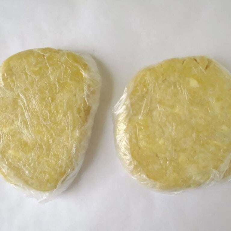 Two discs of homemade pastry wrapped in plastic wrap and ready to use.