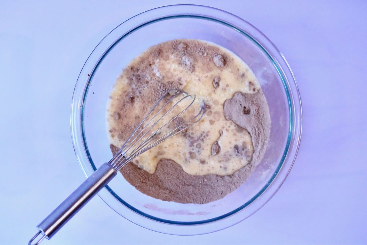 Dry and wet mixture in a glass bowl with a whisk.