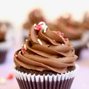 A close up of a decadent chocolate cupcake with a perfect swirl and topped with sprinkles.